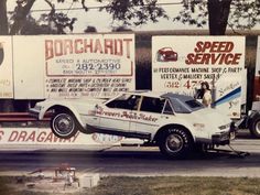 an old time drag car being towed by a tow truck on the side of the road