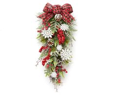 a red and white christmas wreath with pine cones, berries and snowflakes hanging on a wall