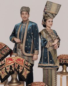 a man and woman dressed in traditional thai garb standing next to each other on stools