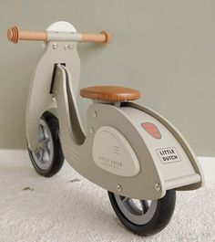 a toy scooter sitting on top of a carpeted floor next to a wall