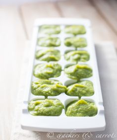 a white tray filled with green food on top of a wooden table