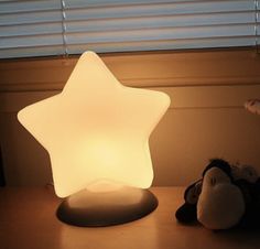 a white star shaped lamp sitting on top of a table next to a stuffed animal