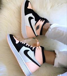 a pair of pink and black sneakers sitting on top of a white fur covered floor