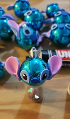 an ornament shaped like a mouse on a table with other ornaments in the background