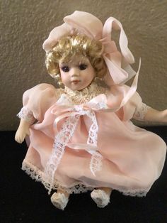 a doll with blonde hair wearing a pink dress and white lace on it's head