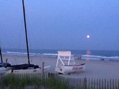 a white chair sitting on top of a sandy beach next to the ocean at night