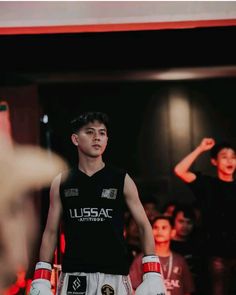 a young man wearing boxing gloves standing in front of a crowd