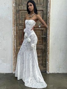 a woman standing in front of a door wearing a white dress