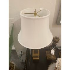 a lamp with a white shade on top of it next to other items in front of a window