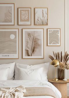 a bed with white sheets and pillows in front of pictures on the wall above it