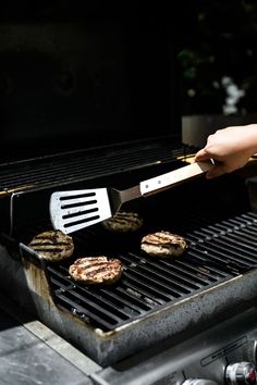 someone is grilling hamburgers on an outdoor grill