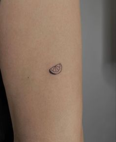 a small tattoo on the back of a woman's left arm, with an orange slice