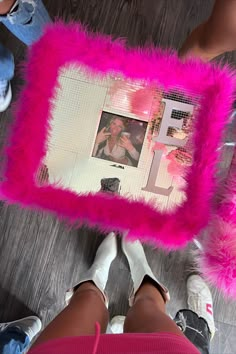 a person holding a pink pillow with a photo on it and some feet in the background