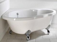 a white bath tub sitting next to a window in a bathroom with tile flooring