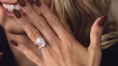 a woman holding her hand up to her face with a diamond ring on it's finger