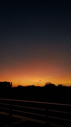 the sun is setting over some buildings and hills in the distance, as seen from a highway