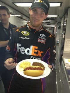 a man holding a plate with a hot dog and some mashed potatoes