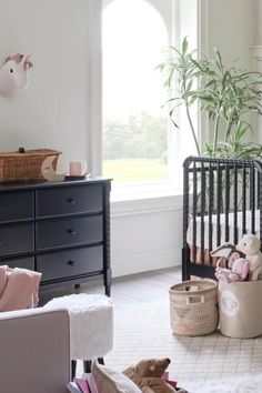 a baby's room with a crib, dresser and stuffed animals in it