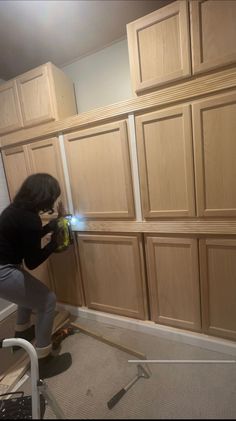 a woman is working on wood cabinets in the kitchen with a light shining through her fingers