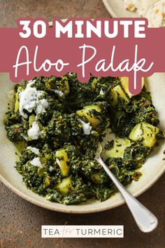 a white bowl filled with spinach and cheese on top of a table next to a spoon