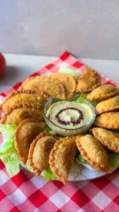 a plate filled with fried food on top of a red and white checkered table cloth