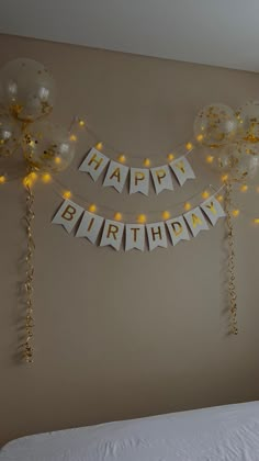 balloons and streamers are hanging on the wall above a bed in a bedroom with a birthday banner