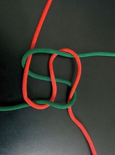 a red and green rope laying on top of a black surface