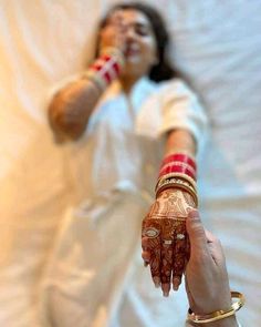 a woman laying in bed with her hands on the wrist and holding something up to her face