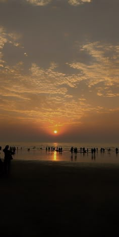 the sun is setting over the beach with people on it