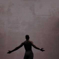 a man standing in front of a wall with his arms outstretched