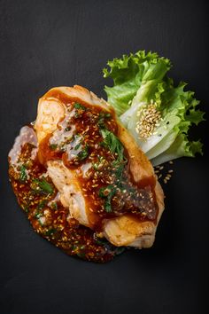 Grilled chicken breast topped with a savory sesame sauce, garnished with fresh lettuce and sesame seeds.