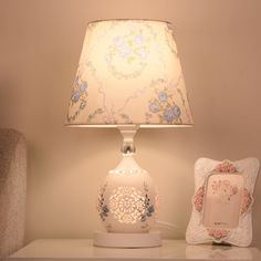 a lamp on a table next to a small photo frame and an old - fashioned phone