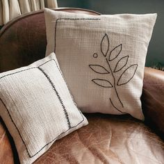 two pillows sitting on top of a brown chair