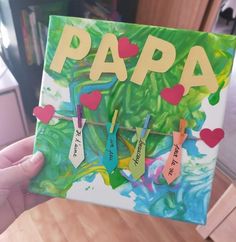 someone is holding up a card with the words papa on it and hearts hanging from clothes pins