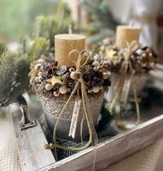 two candles are sitting on a tray decorated with pine cones and other holiday decor items