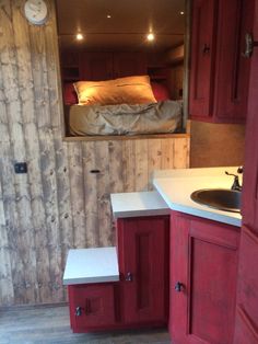 a small kitchen area with sink, cabinets and bed in the back wall behind it