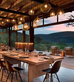 an outdoor dining area with wooden tables and chairs, overlooking the valley outside at dusk