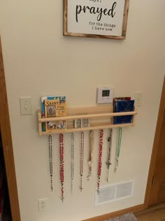 a wooden shelf filled with lots of necklaces on top of a wall next to a door