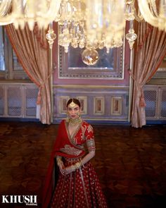 a woman in a red and gold bridal gown standing next to a chandelier