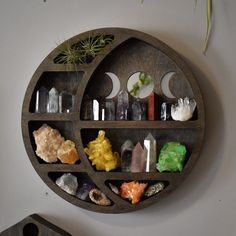 a circular wooden shelf filled with different types of rocks and crystals on top of a white wall