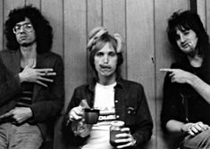 three women sitting next to each other in front of a wooden wall holding coffee cups