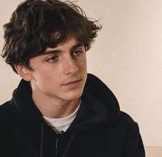 a young man wearing a black hoodie and looking at the camera with an intense look on his face