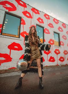 a woman standing in front of a wall with orange and black graffiti