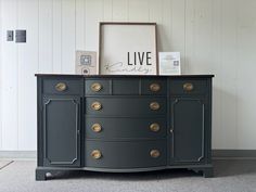 a black dresser with gold knobs and a live sign on it's top