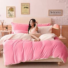 a woman sitting on top of a bed with pink sheets and pillows in front of her