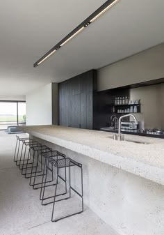 a long counter with stools in front of it and an open kitchen area to the side