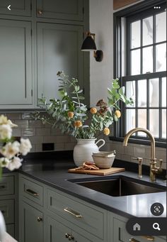 a vase with flowers in it sitting on a kitchen counter next to a sink and window