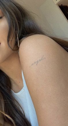 a woman with a small tattoo on her left arm and right arm behind her head