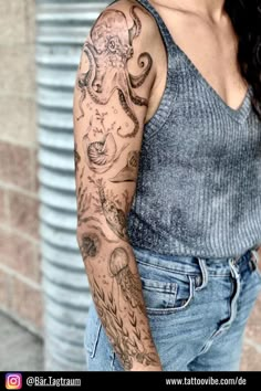 a woman with a octopus tattoo on her arm and shoulder is standing in front of a brick wall