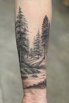 a man's arm with a forest scene on it